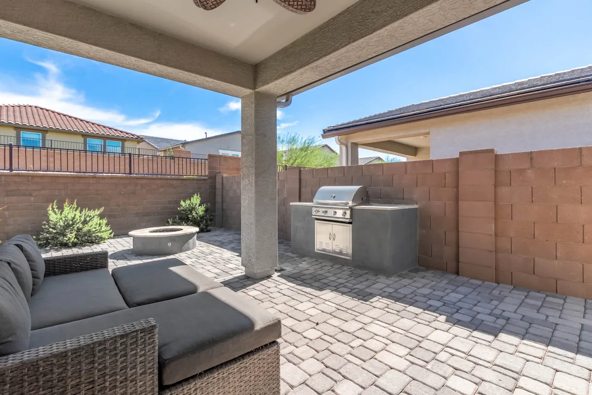 This image showcases an inviting outdoor seating area equipped with a grill and a fire pit. Surrounded by comfortable chairs, the space is designed for both relaxation and entertaining, with elements perfect for hosting barbecues or gathering with friends under the evening sky.