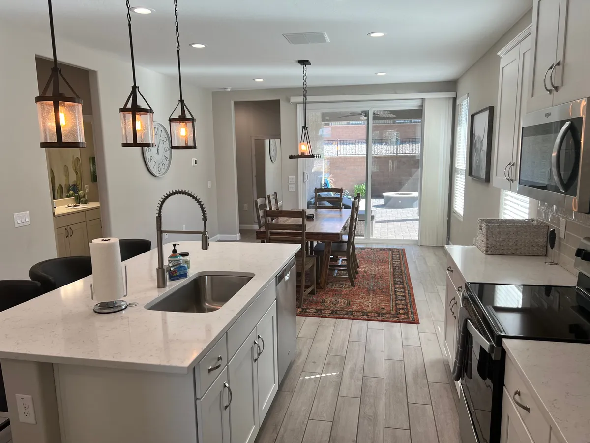A stylish and inviting kitchen with an island, dining table, and warm pendant lighting. The space is set for cooking, dining, and socializing, with modern fixtures and a welcoming ambiance that reflects Southwestern chic design.