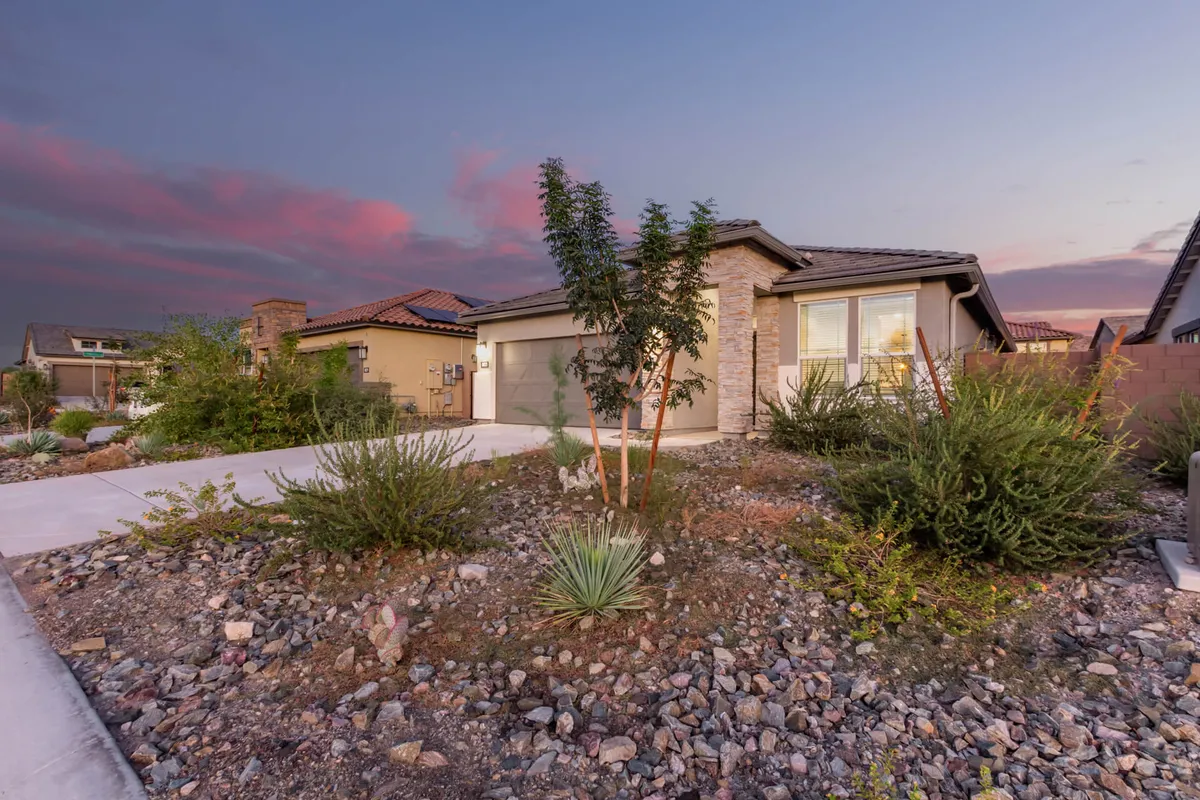 A welcoming view of the home's front facade, landscaped garden, and driveway. The soft lighting and charming exterior evoke feelings of arrival and comfort, highlighting the property's inviting atmosphere and its connection to the surrounding neighborhood.