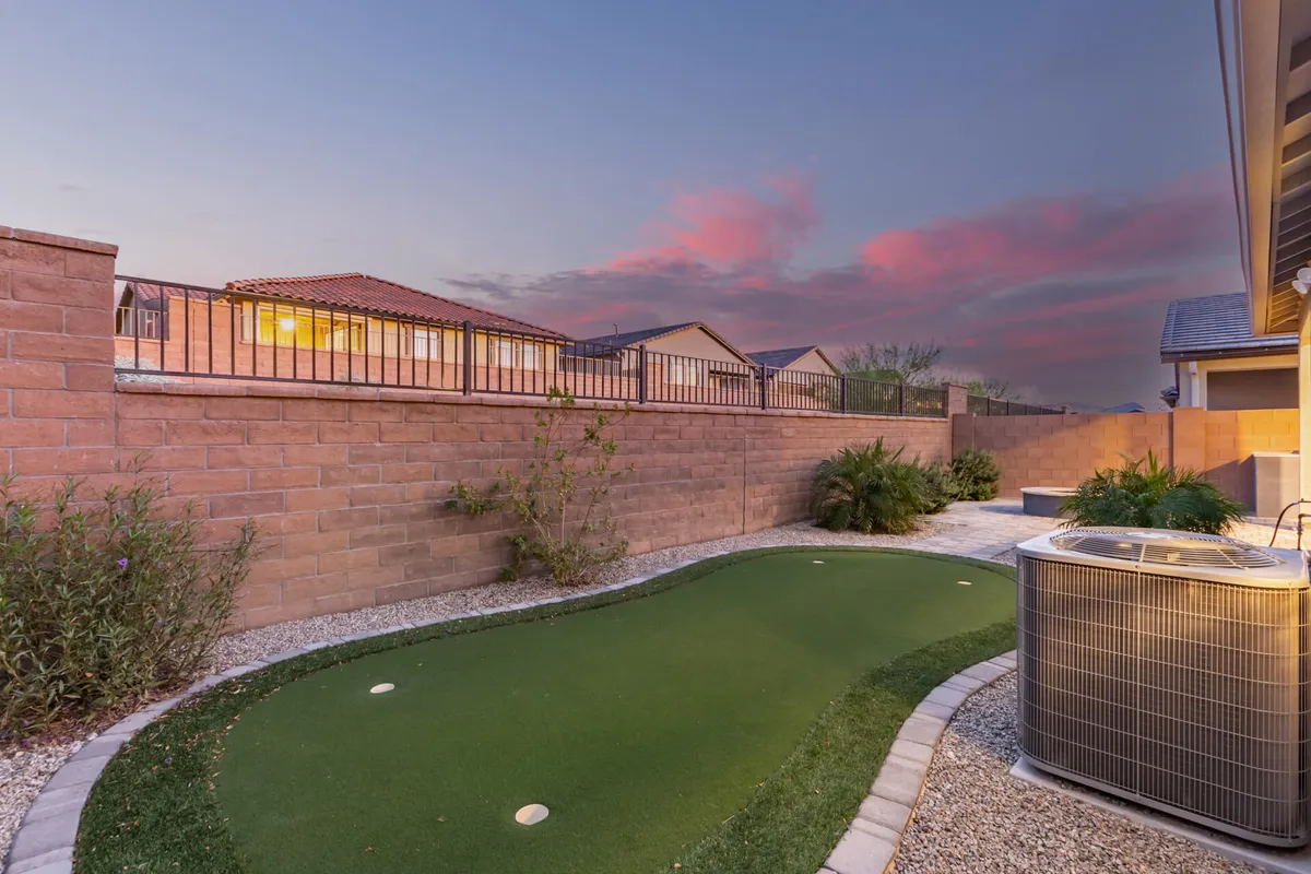 A backyard scene featuring an artificial putting green, landscaped area, and boundary wall. The leisurely mood reflects outdoor enjoyment, social gatherings, and activities like golf practice, resonating with the sporty, energetic tone of the section.