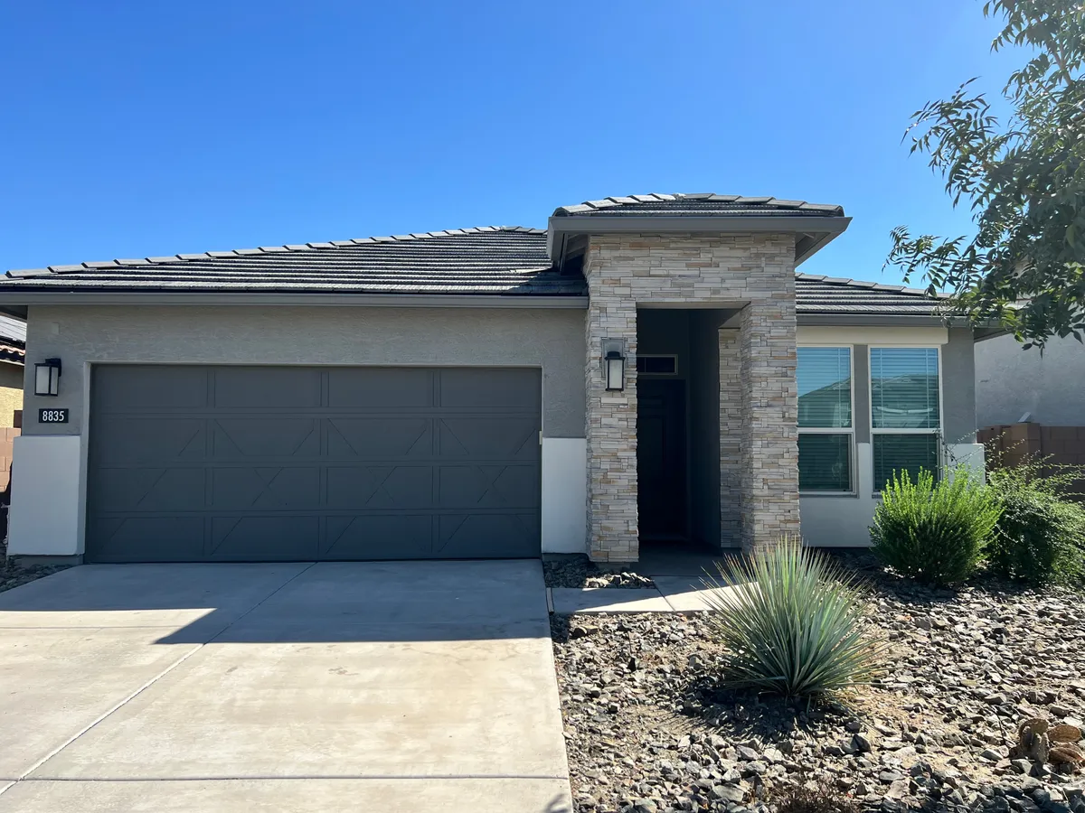 This image showcases the home's front entrance with a stone facade, garage door, and manicured landscaping. The inviting mood suggests the comfort and relaxation awaiting after a day of nearby sports excitement.